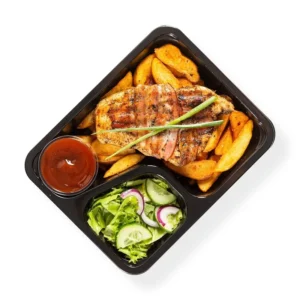 Posilkiregeneracyjnezkielbasaijajkiem Grilled fish fillet on potato wedges with a side salad lettuce cucumber red onion and red sauce in a black meal tray