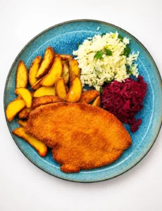 Zupapomidorowazmakaronemdomowyobiad Golden fried breaded chicken breast with potato wedges white rice with green onions and shredded beets on a blue plate